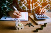 Person calculating mortgage with house model