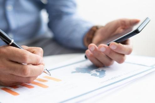 person writing notes while checking phone