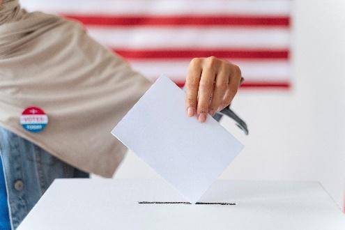 Person casting ballot with American flag background