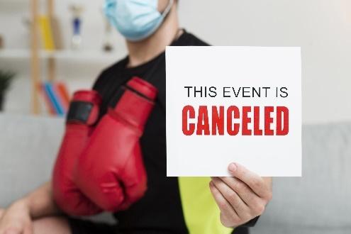 Person in mask and gloves holding cancellation sign