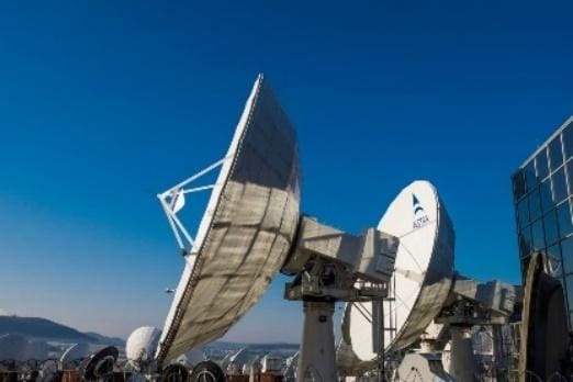 Large satellite dishes under clear blue sky.
