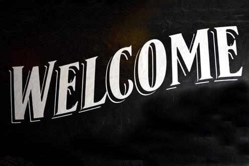 Large vintage white WELCOME sign on black