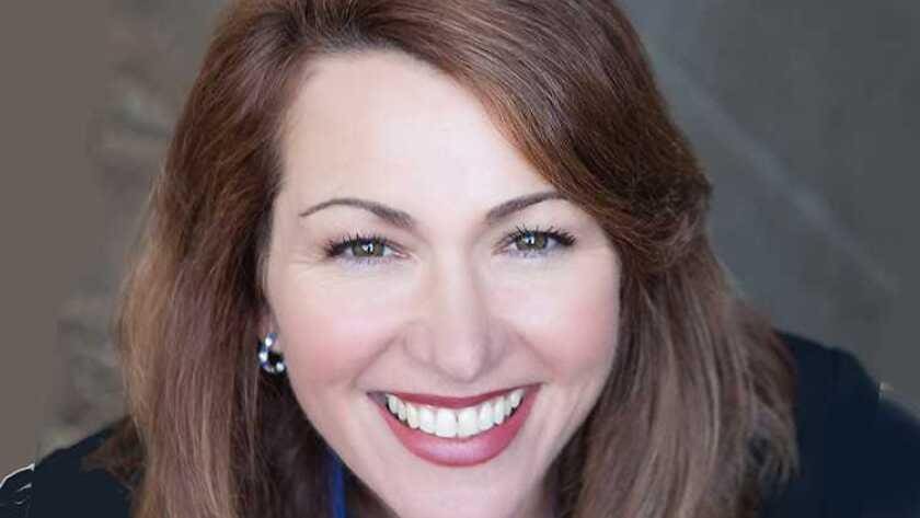 Smiling woman with brown hair and earrings.