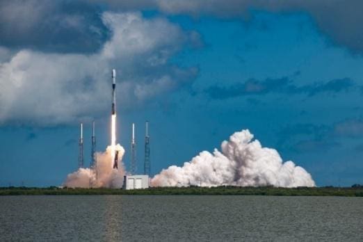 Rocket launching into the sky with smoke and water below.