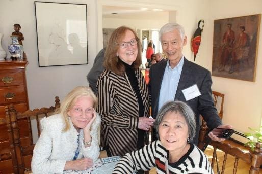 A group of four diverse people smiling and posing indoors.