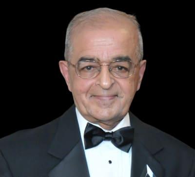 Elderly man in tuxedo with glasses.