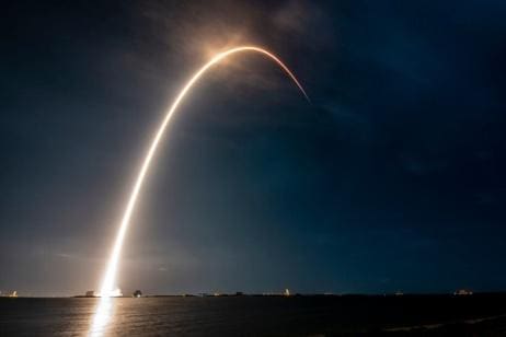 Rocket launching into the night sky with a bright trail.