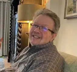 Smiling man in glasses sitting on patterned couch