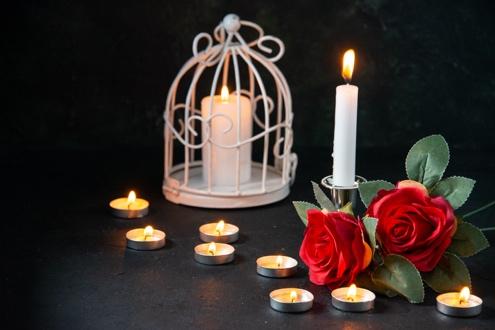 Candles and roses on a dark surface.