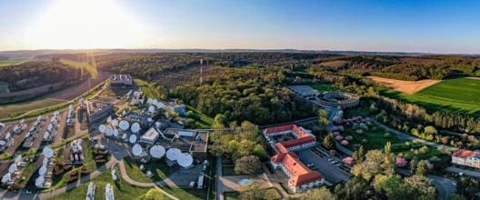 Aerial view of a large green forest area surrounded by buildings under a clear sky.