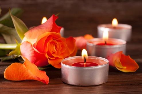 Rose and tealights on wooden surface.
