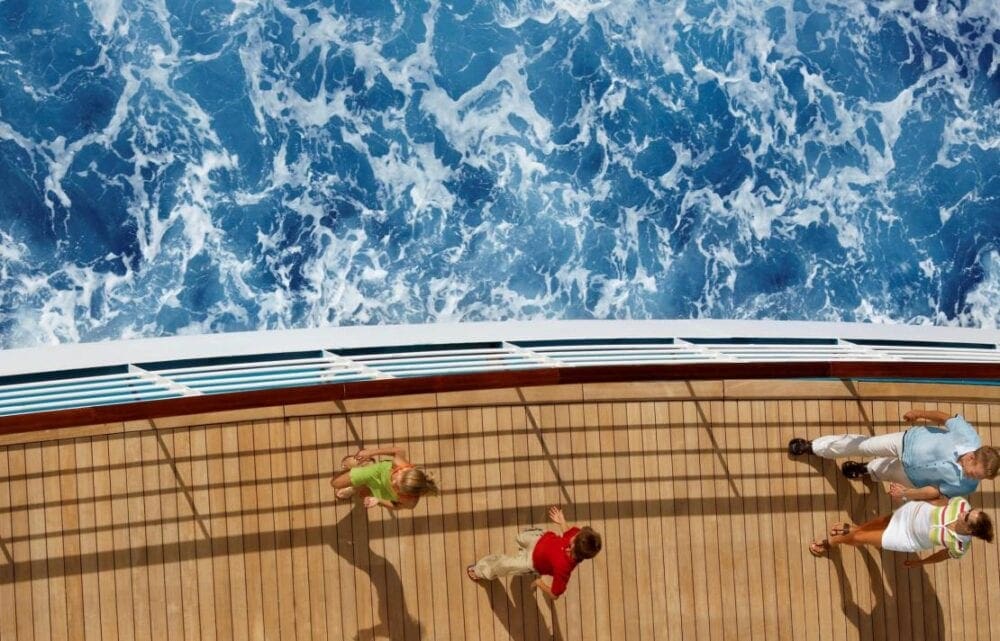 View from a ship's deck showing the ocean waves and two people walking.