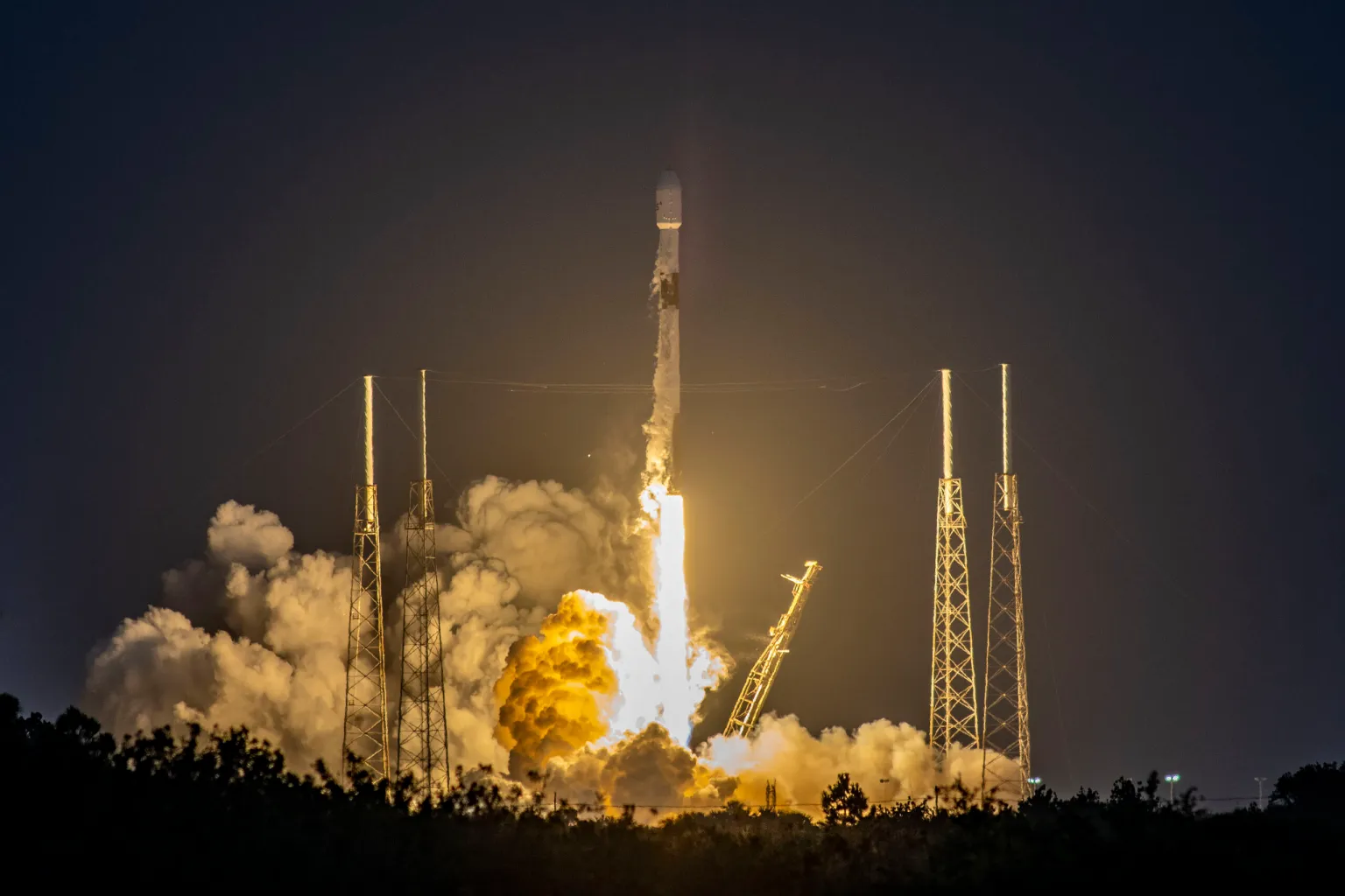 Slim rocket rising with glowing exhaust plume