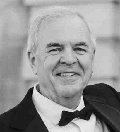 Portrait of an elderly man in formal attire, smiling.