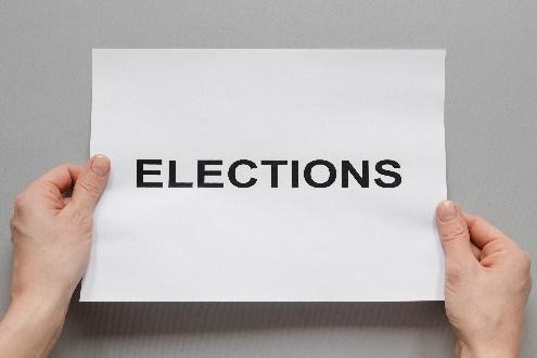 Hands holding paper reading ELECTIONS