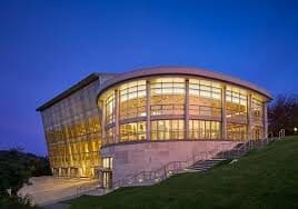 Modern glass building illuminated at dusk with a curved design.