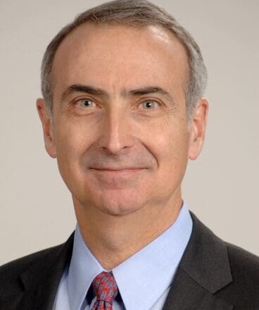 Portrait of a middle-aged man in a suit with a neutral background.