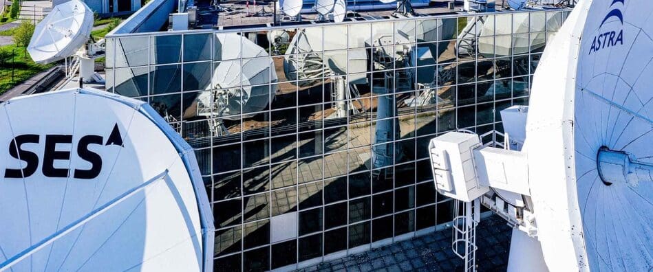 Satellite dishes behind a metal fence in an outdoor area.