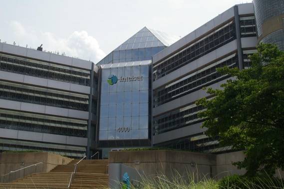 Modern glass and steel office building with a pyramid-shaped roof.