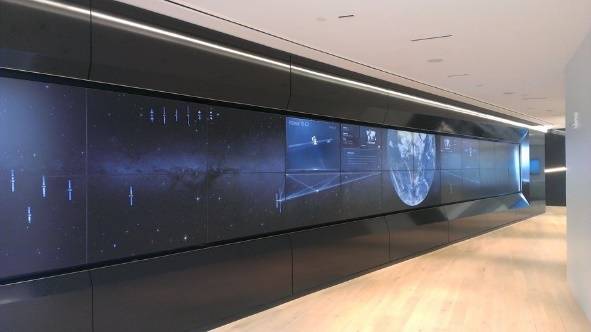 Futuristic digital wall display with a space theme in a modern hallway.