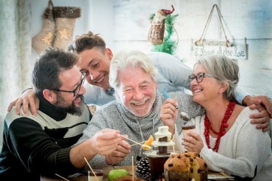 Three elderly friends joyfully sharing dessert at a cozy gathering.