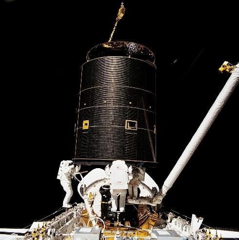 Close-up of a spacecraft's black cylindrical component against a black background.