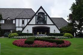 Elegant Tudor-style house with manicured gardens and vibrant flower beds.