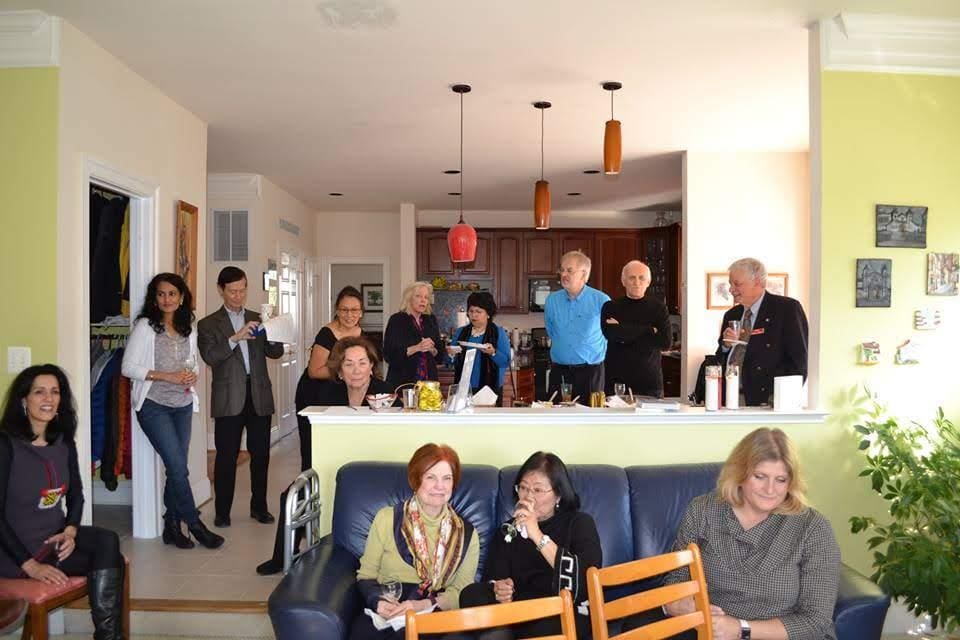 A group of people gathered in a cozy living room, smiling and posing for a photo.