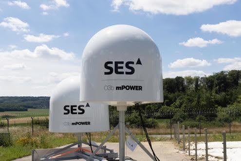 Two SES satellite dishes under a partly cloudy sky.