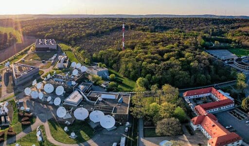 Aerial view of a green forest area adjacent to a facility with large storage tanks.