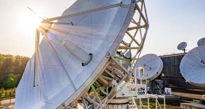 Close-up of parabolic satellite dishes with sun flare