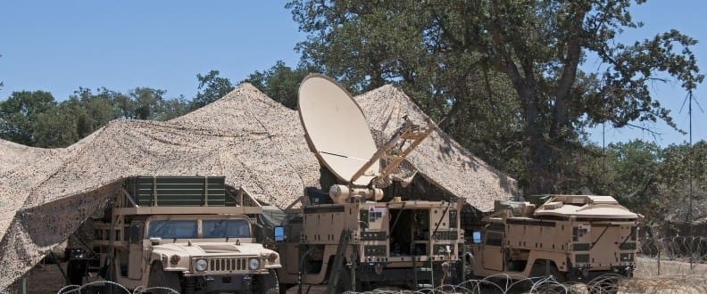 Fielded mobile satellite communications vehicles under netting