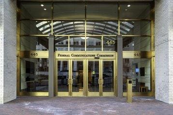 Entrance to the Federal Communications Commission building with glass doors.