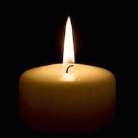 A single lit candle with a glowing flame against a dark background.