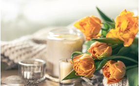 Orange tulips with candles on table.