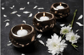 Candles and white flowers on dark background.