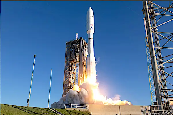 White rocket ascending beside gantry at sunrise
