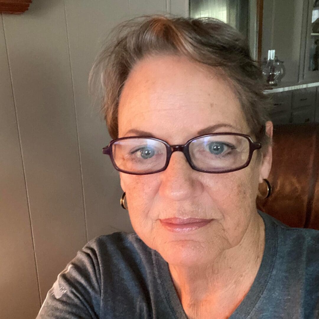 Elderly woman wearing glasses, looking at camera.