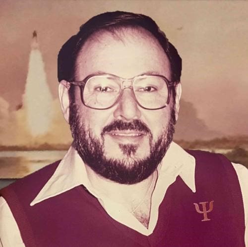 Man smiling with rocket launch background.