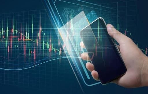 Hand holding smartphone with digital financial graphs.