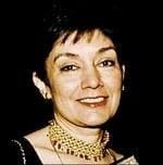 Woman smiling, wearing a gold necklace.