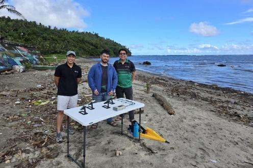 Three people with drones on a beach.