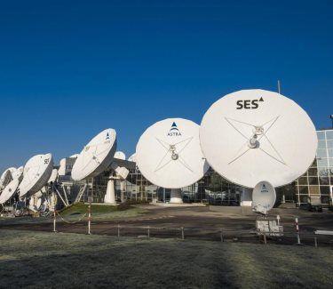 Satellite dishes aligned in a row outdoors.