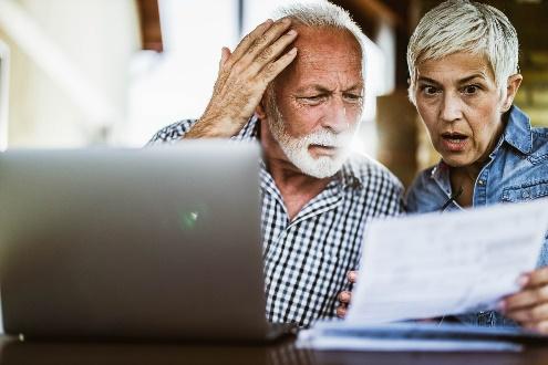 Elderly couple surprised by document on laptop.
