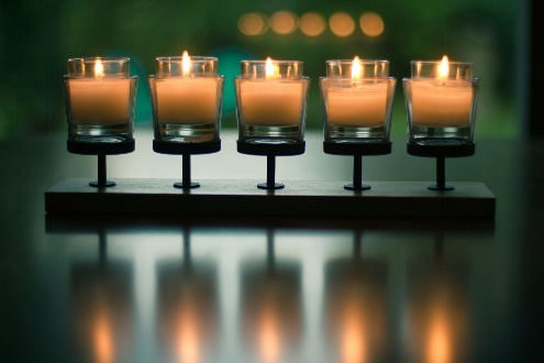 Five lit candles on a wooden holder.