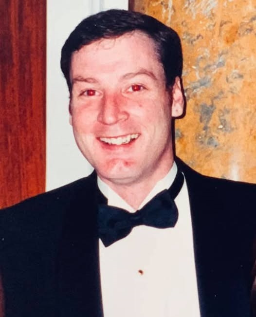 Man in tuxedo smiling at event.