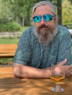 Bearded man in sunglasses at outdoor table