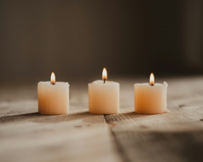 Three lit candles on wooden surface.