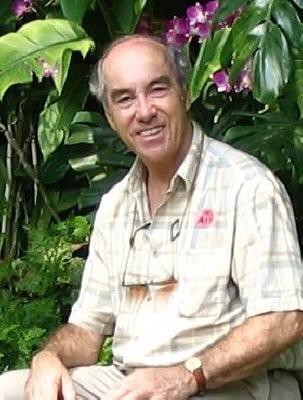 Smiling man seated among purple orchids