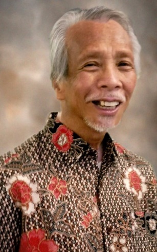 Smiling man in floral patterned shirt.